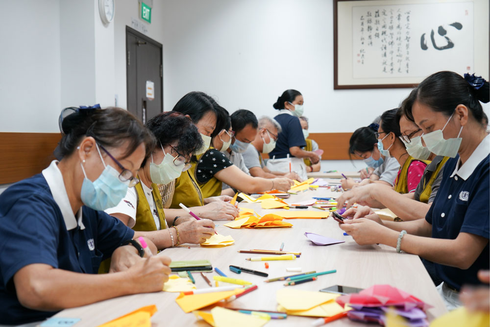 Volunteers are folding origami hearts and writing down words of blessings on them. Photo by Chan May Ching